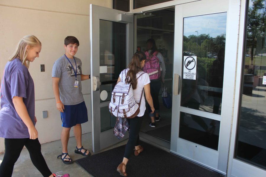 Austin Grumbles holding the door for Brittaney Kelley and Kendall Silvers