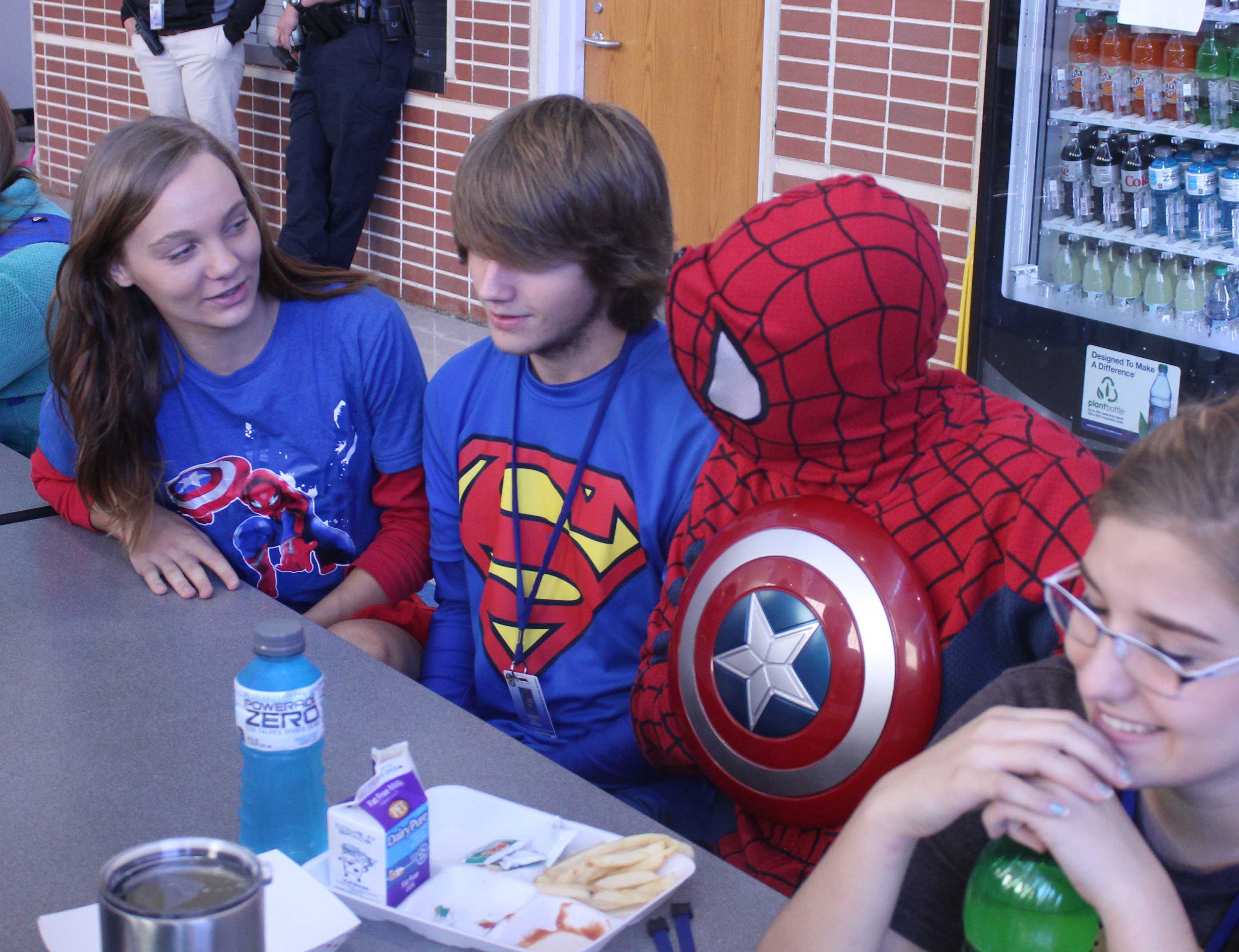 Students eat lunch in their DC and Marvel attire.