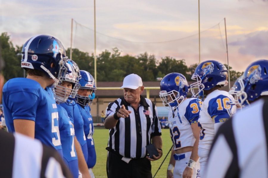 Referee addresses team captains during coin toss. 